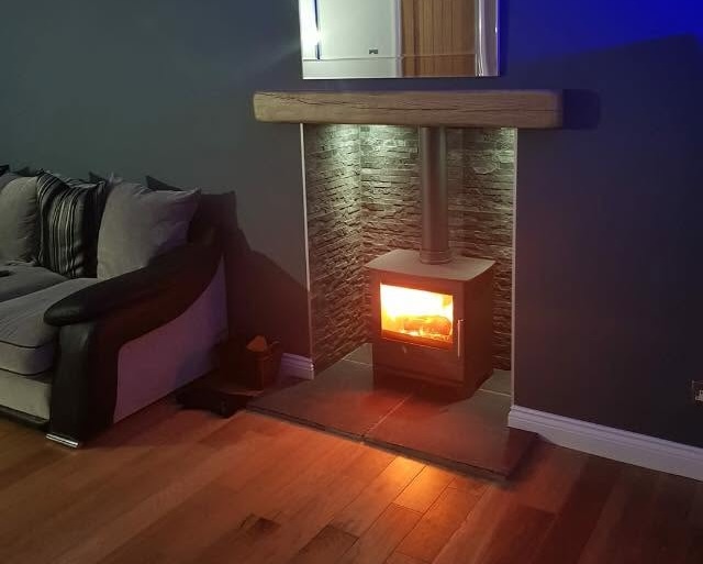 Modern log burner installed with a stone surround and wooden mantel